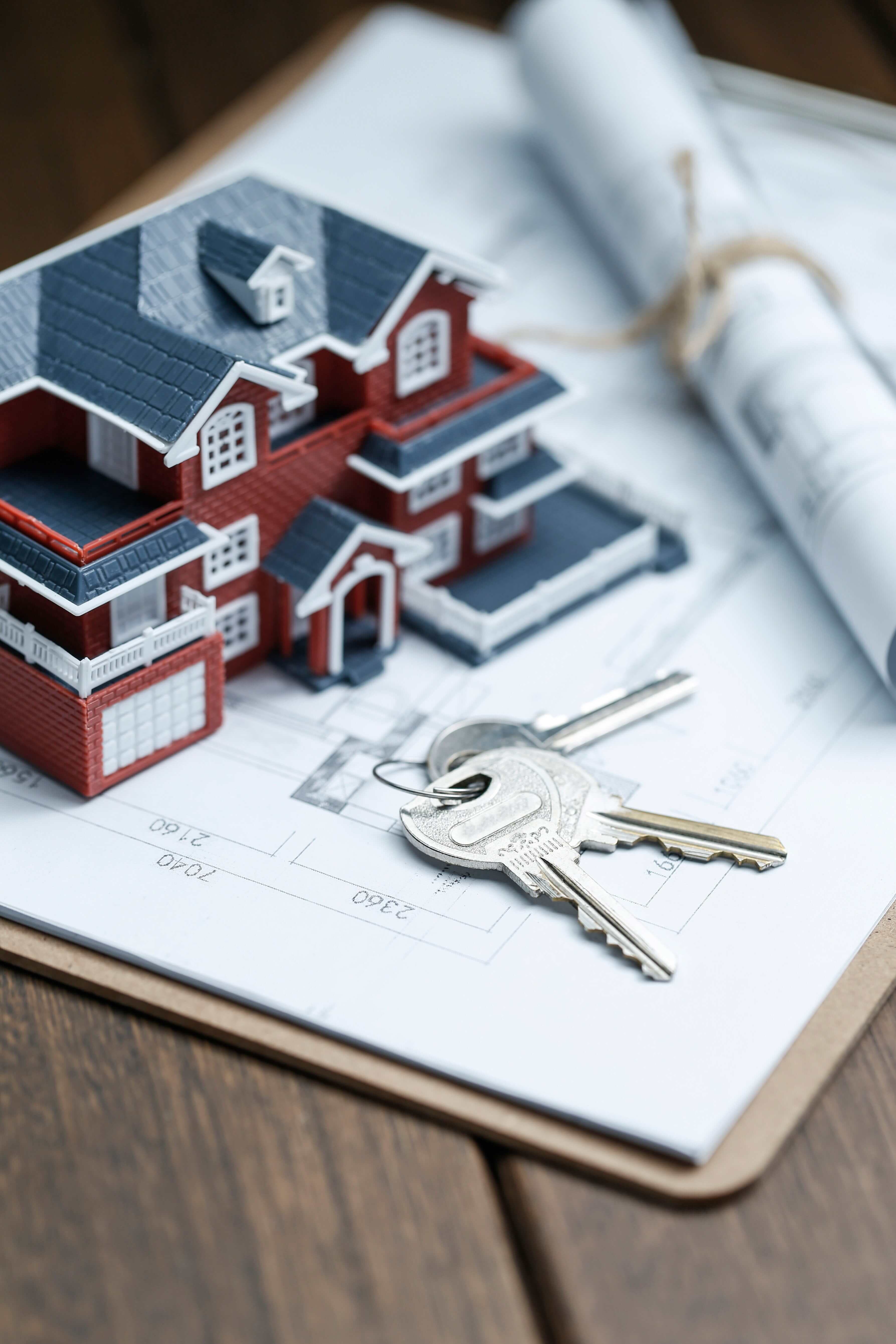A model house and keys resting on a set of building plans