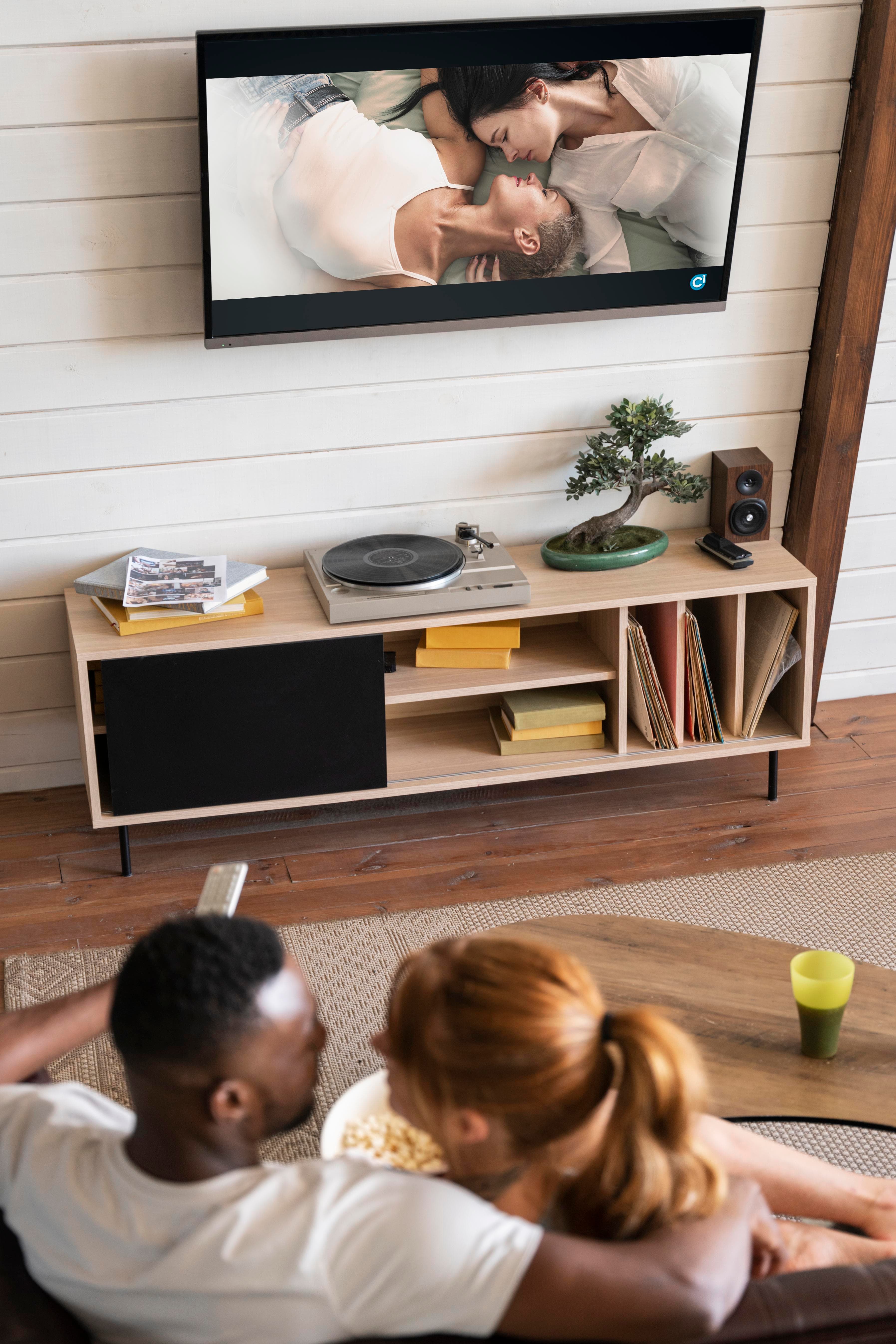 A couple relaxing in a styled living room with a wall-mounted television